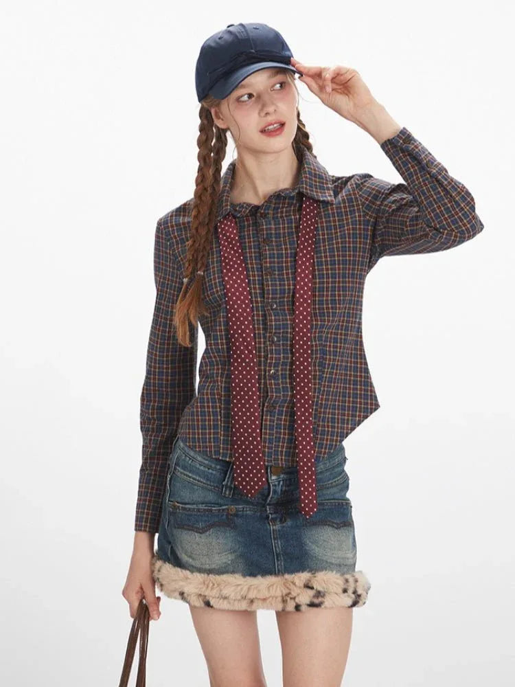 Woman in a plaid shirt, denim skirt, and baseball cap adjusting her cap, holding a brown handbag.