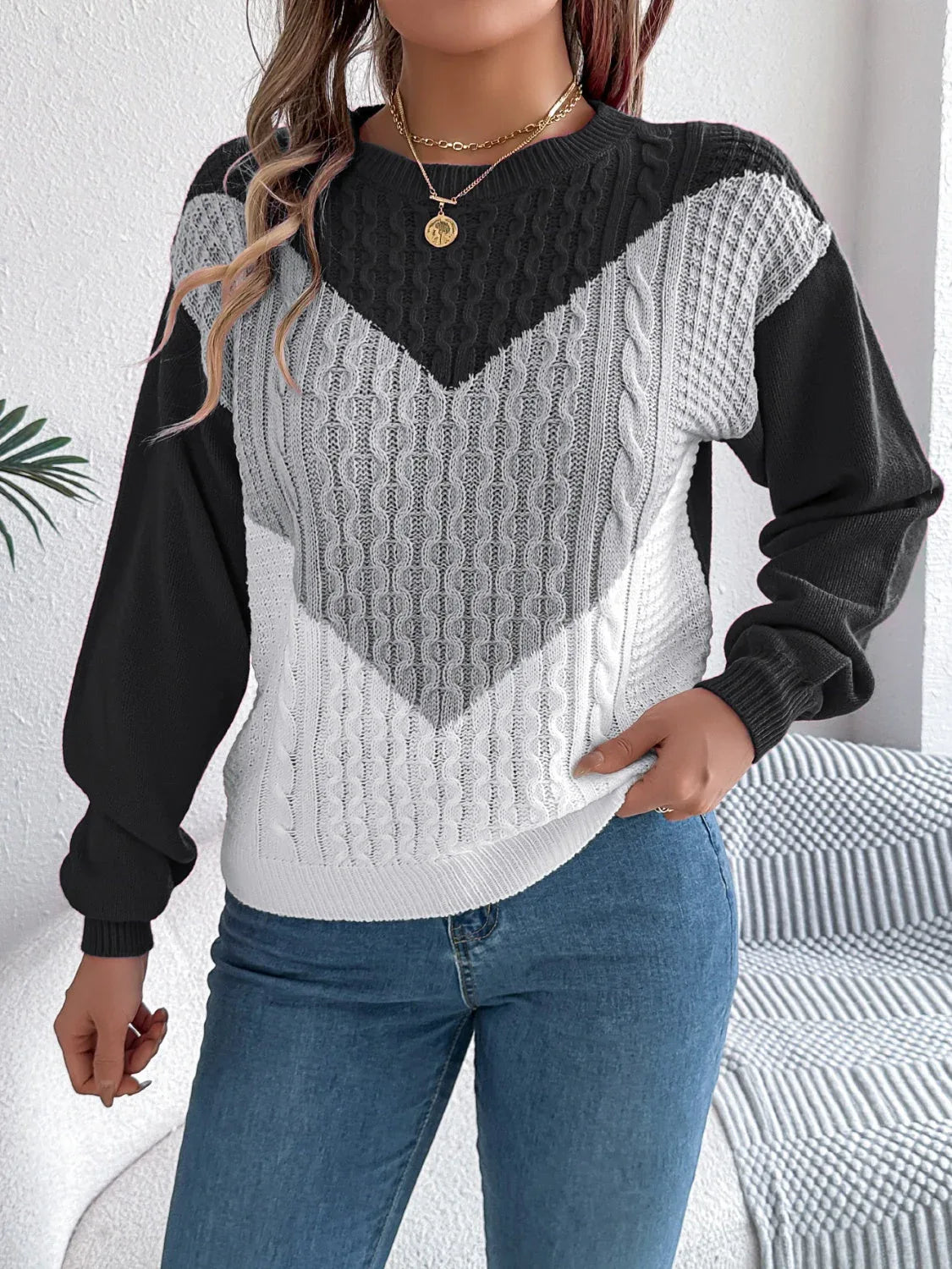 Front view of a woman styling a color block sweater with accessories.
