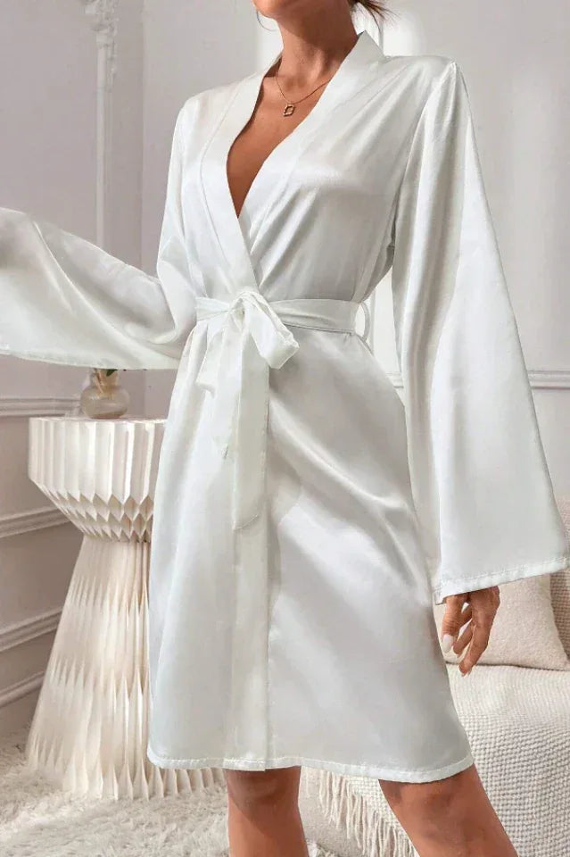 Woman wearing a white satin robe with bell sleeves and a self-tie belt.
