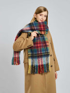 Woman adjusting a large plaid scarf with fringe details