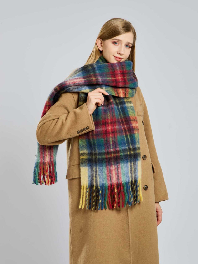 Woman adjusting a large plaid scarf with fringe details