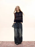 Woman wearing a navy button-down cardigan with a Fair Isle knit pattern and pink accents, white t-shirt, wide-leg jeans, and a crossbody bag.