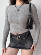 Woman wearing a grey cable knit cropped sweater with a black denim skirt and a black belt