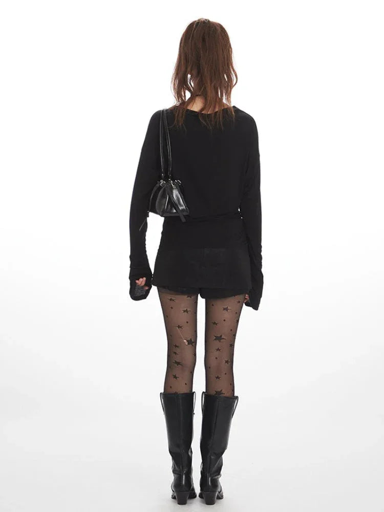 Model wearing a black long-sleeved top and star-print tights from the front.