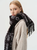 Close-up of a woman wearing a black scarf with white text and fringe