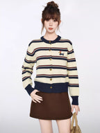 Close-up of a knit cardigan featuring a striped pattern and a small embroidered dog wearing a hat