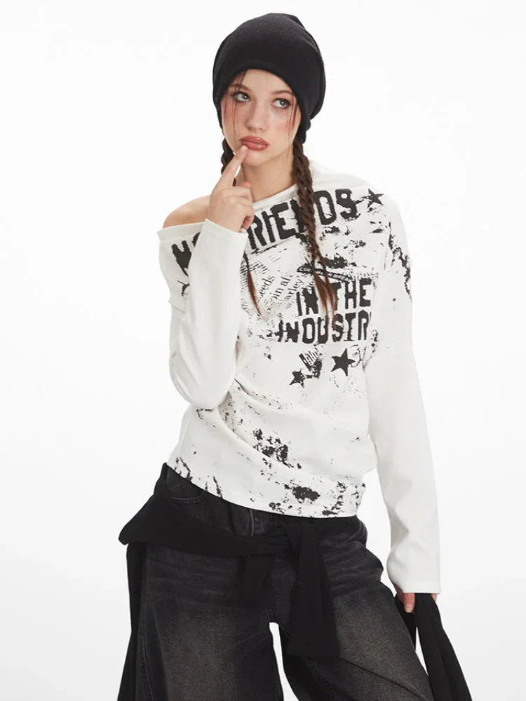 Close-up of a woman wearing a white long-sleeve graphic print top with an off-the-shoulder design.