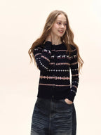 Woman wearing a navy button-down cardigan with a Fair Isle knit pattern and pink accents, and a white t-shirt.