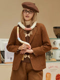 Woman posing in a brown blazer, layered over a turtleneck and sweater, with a beret and scarf.