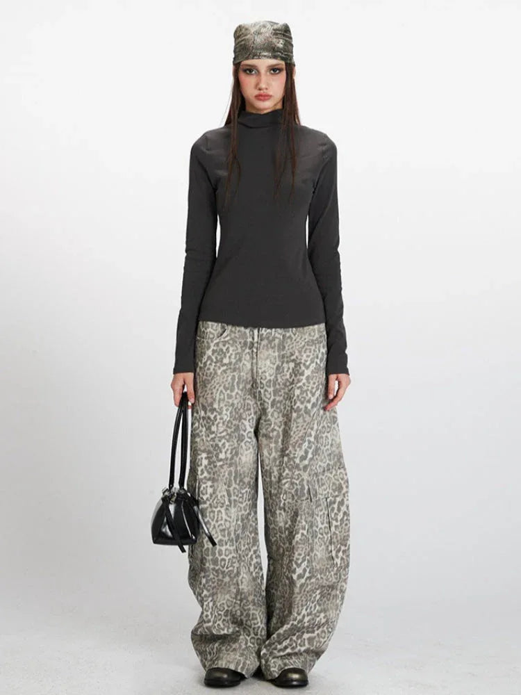 Model wearing a dark grey mock neck long sleeve top and patterned wide-leg pants.