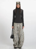 Model wearing a dark grey mock neck long sleeve top and patterned wide-leg pants.