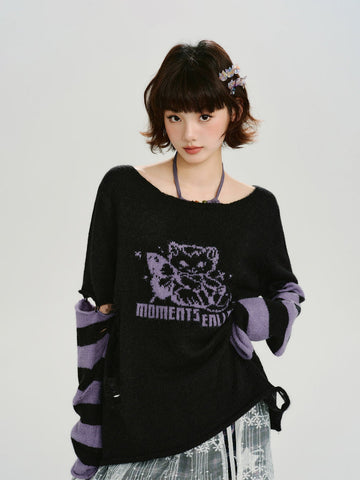 Woman wearing a black oversized knit sweater with a purple graphic print and distressed details.