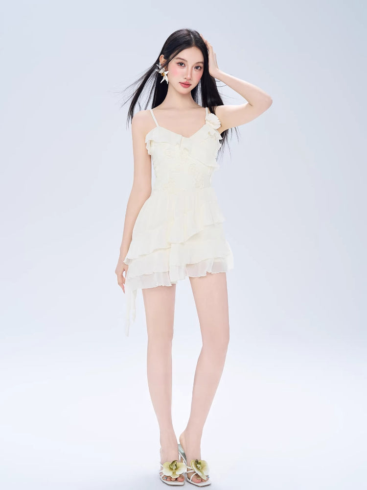 Woman wearing a cream-colored mini dress with spaghetti straps and ruffle detailing.