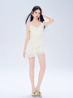 Full body shot of a woman in a cream-colored mini dress with layered skirt.