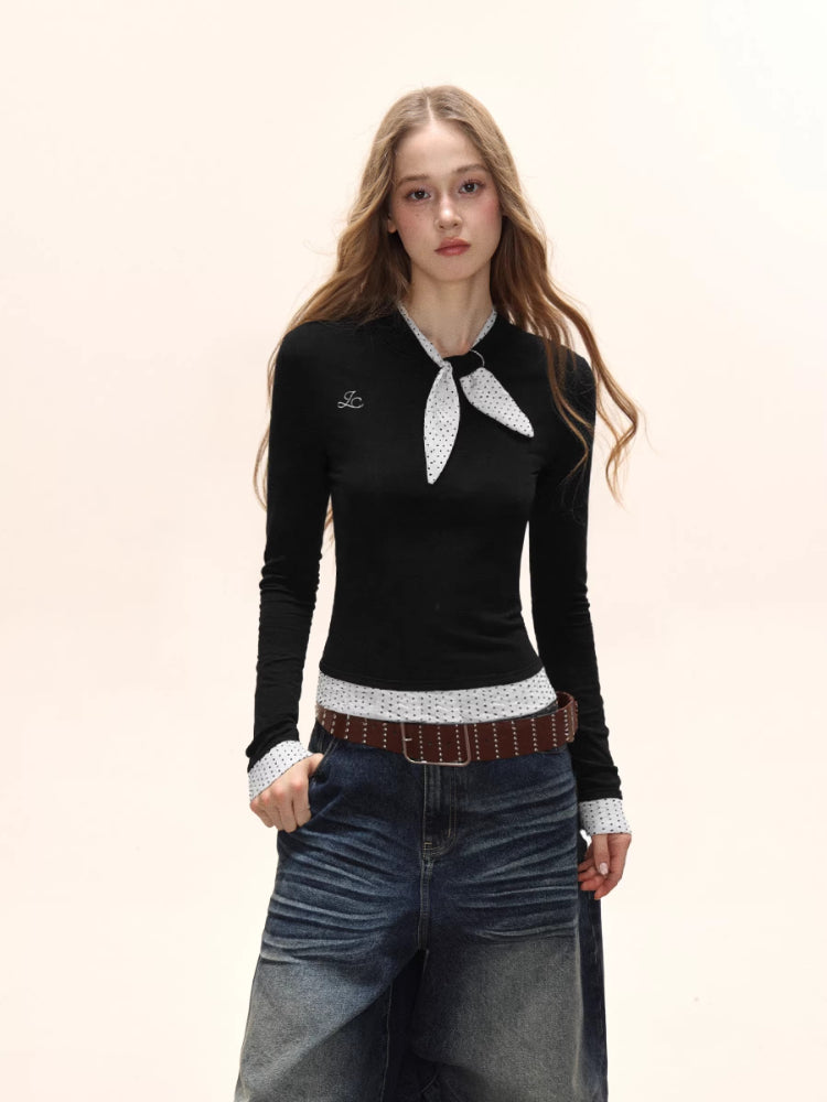 Model wearing a black long-sleeve top with white polka dot trim and scarf detail