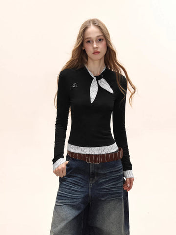Model wearing a black long-sleeve top with white polka dot trim and scarf detail