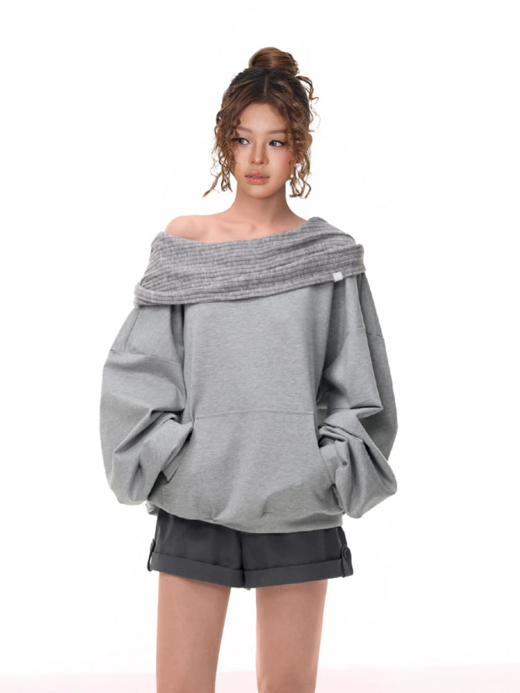 Woman wearing a grey off-the-shoulder sweatshirt with balloon sleeves and a ribbed cowl neck detail