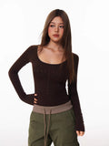 Model posing in a brown long-sleeve top and olive green cargo pants