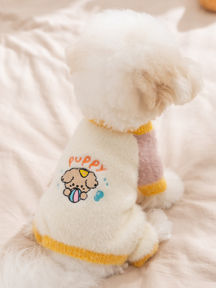 Back view of a Bichon Frise dog wearing a knit sweater with embroidered puppy graphic