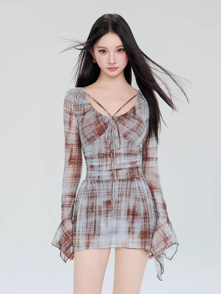 Woman wearing a long-sleeved plaid mini dress with a tie-front detail and flared sleeves