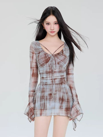 Woman wearing a long-sleeved plaid mini dress with a tie-front detail and flared sleeves