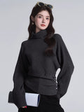 Model posing in a dark grey high neck knit sweater