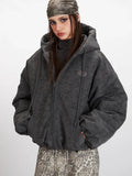 Woman in a charcoal grey textured puffer jacket with hands in pockets.