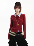 Woman wearing a red cable knit cardigan with a blue collared shirt underneath and a gold cross necklace.