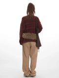 Back view of a woman in a maroon and brown striped oversized knit sweater.