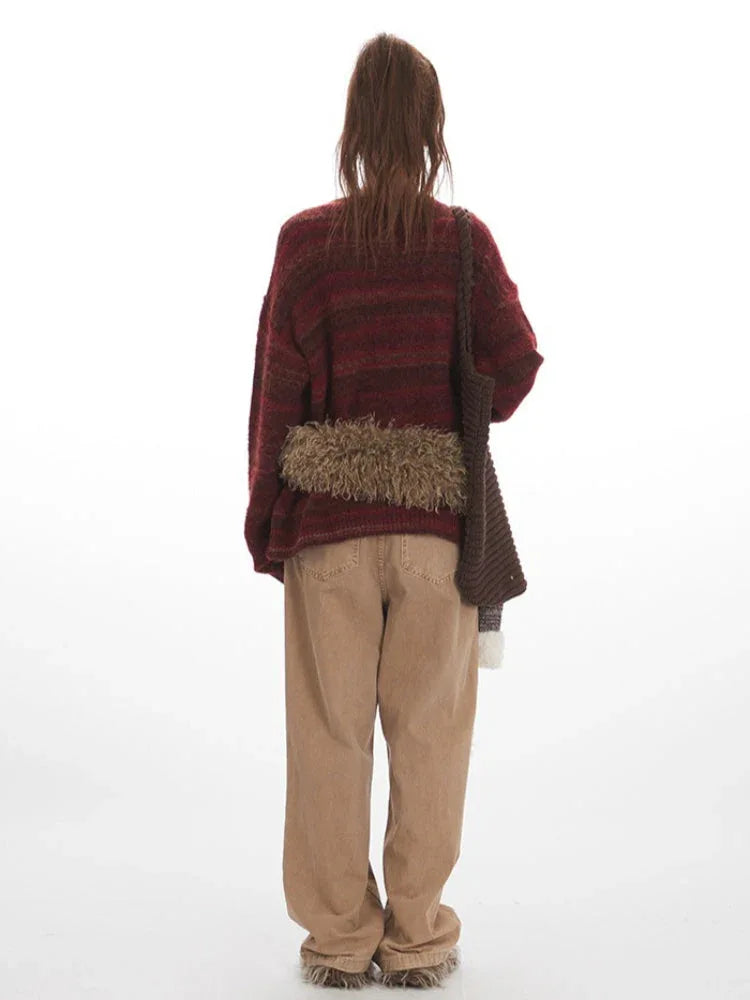 Back view of a woman in a maroon and brown striped oversized knit sweater.