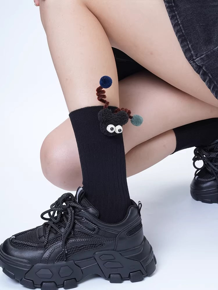 Black crew socks with a black creature applique and pom-poms