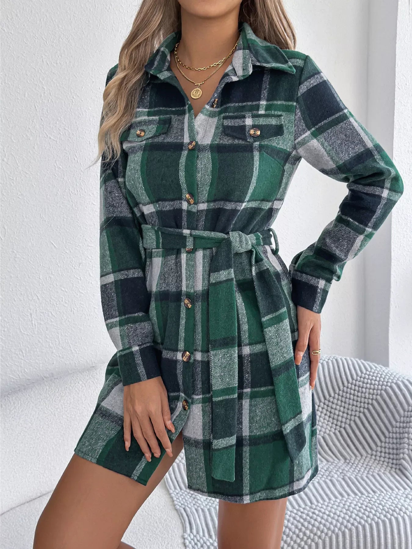 Woman wearing a green plaid flannel shirt dress with a tie waist.