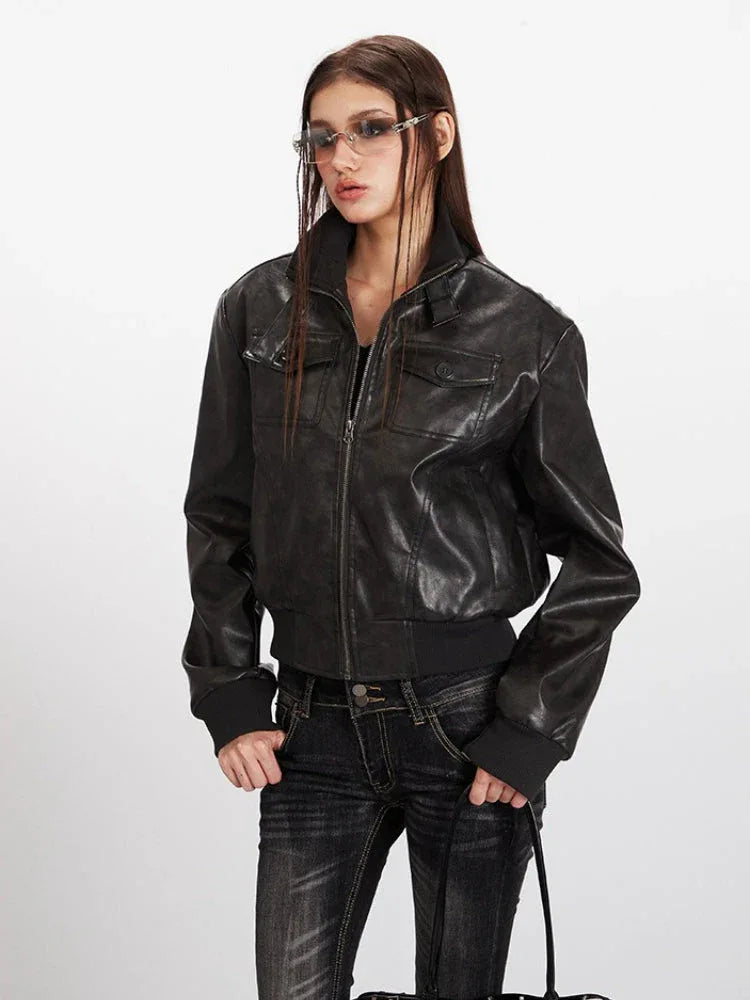 Close-up front view of a woman wearing a black faux leather bomber jacket with zipper closure and chest pockets.