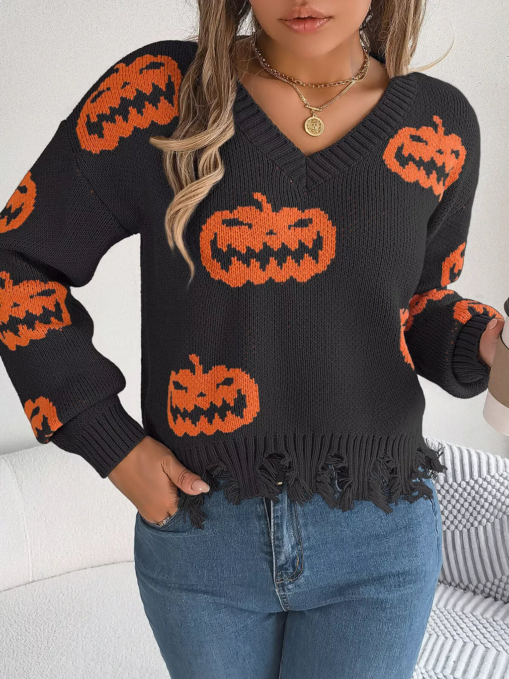 Woman with blonde hair wearing a black and orange pumpkin sweater