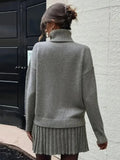 Back view of a woman wearing a grey knit turtleneck sweater and a matching grey pleated mini skirt.