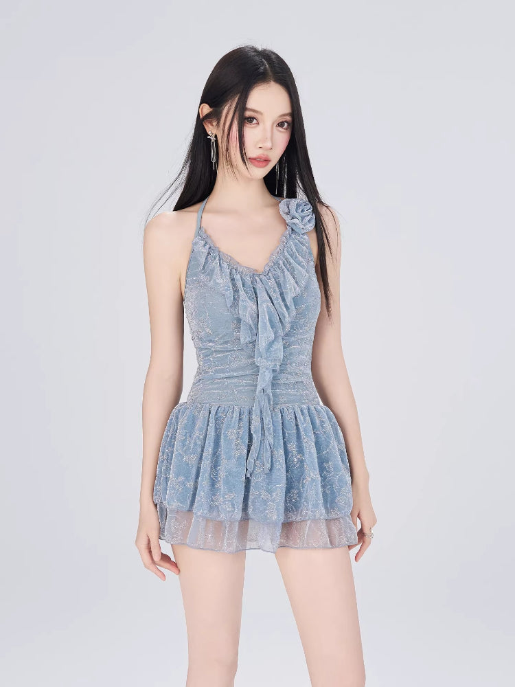 Model posing in a light blue textured lace halter dress with floral applique