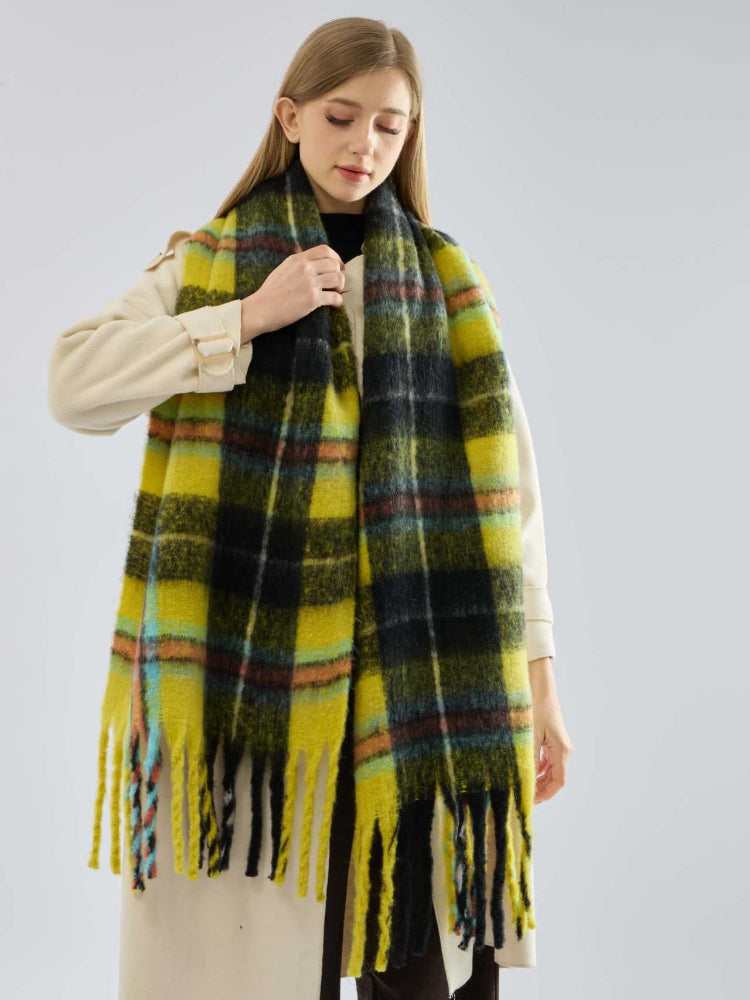 close-up of a woman's hands and arms, wearing a grey ribbed sweater, with a plaid scarf wrapped around her neck