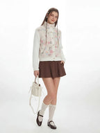 Front view of a woman in a white floral print fleece jacket with cable knit sleeves.