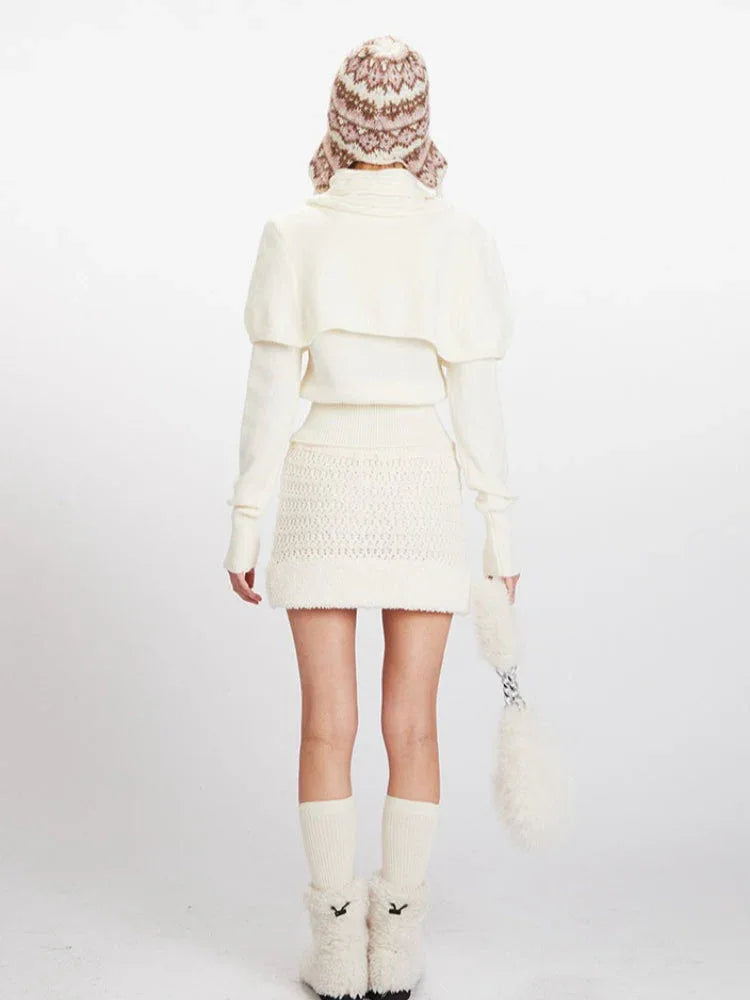 Woman wearing a cream knit turtleneck sweater with puffed sleeves over a cream knit mini skirt with a drawstring waist.