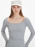 Close-up of a woman's upper body wearing a grey long-sleeved ribbed knit top with a scoop neckline.