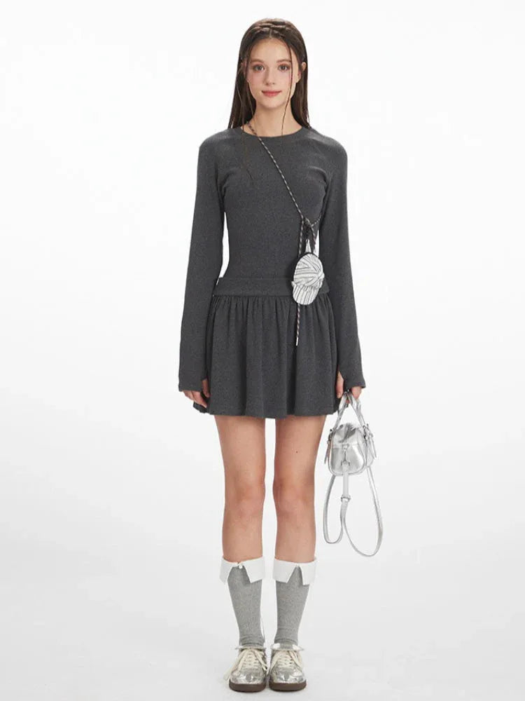 Model wearing a dark grey ribbed drop waist mini dress with long sleeves and crew neckline.
