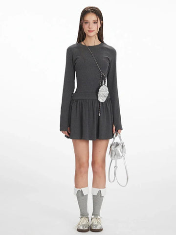 Model wearing a dark grey ribbed drop waist mini dress with long sleeves and crew neckline.