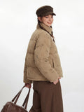 Side view of a woman in a tan corduroy puffer jacket with a dog print, smiling.