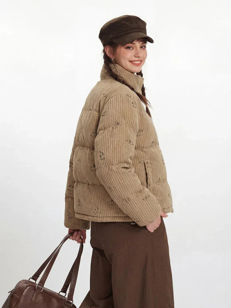 Side view of a woman in a tan corduroy puffer jacket with a dog print, smiling.