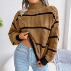 Woman wearing a tan and black striped knit mock neck sweater with light wash denim jeans