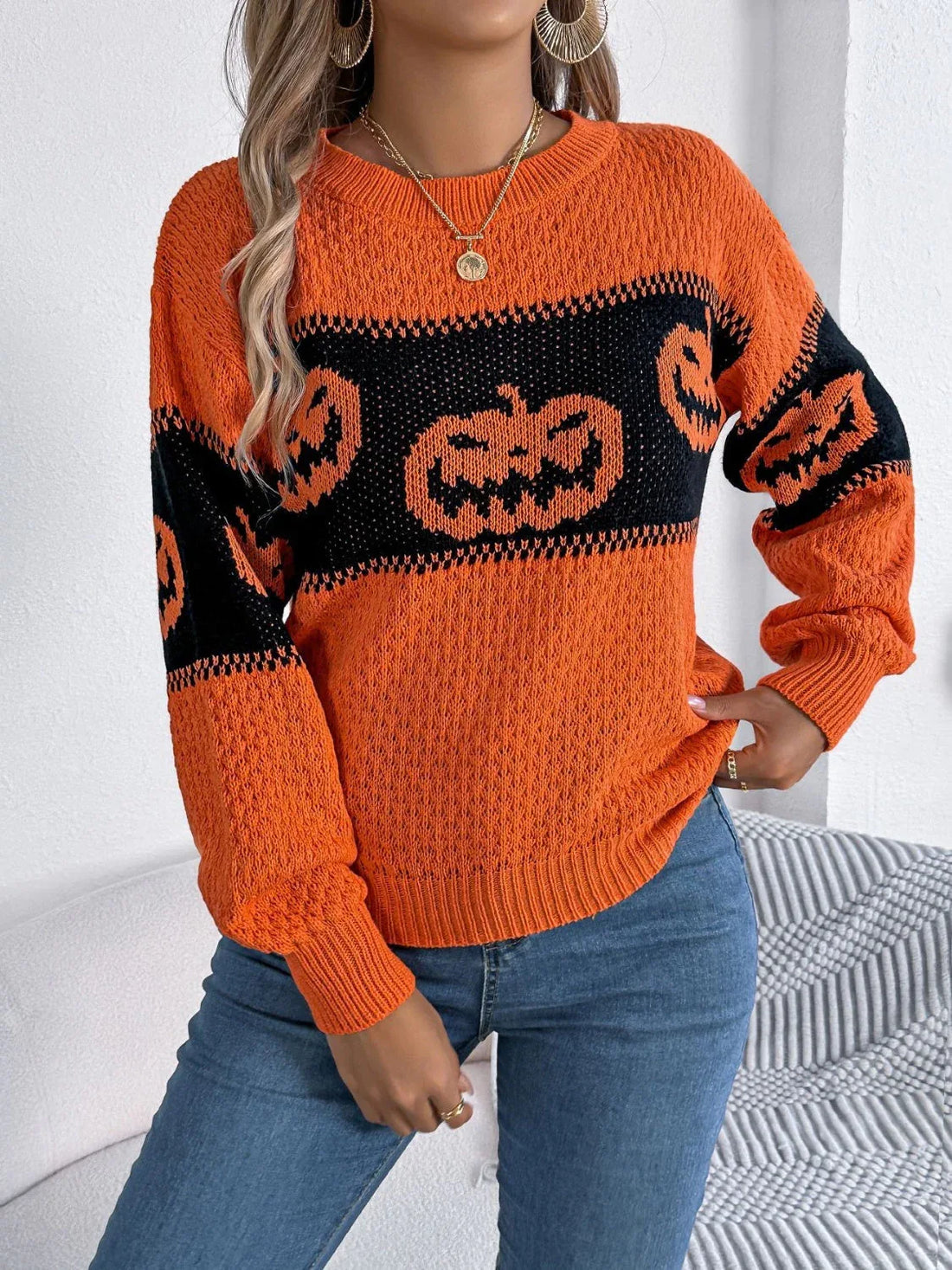 Woman wearing an orange and black striped knit sweater with pumpkin graphics.