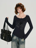 Woman posing with a black handbag while wearing a dark blue long-sleeve graphic t-shirt