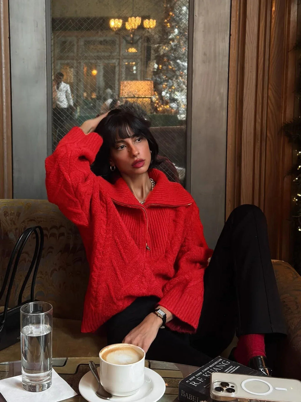 Woman wearing a red textured knit half-zip sweater and black pants, posing indoors.