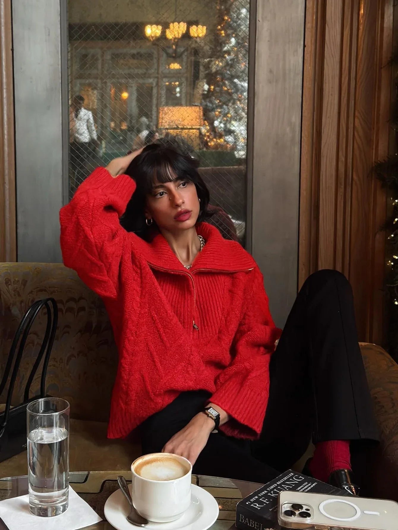 Woman wearing a red textured knit half-zip sweater and black pants, posing indoors.