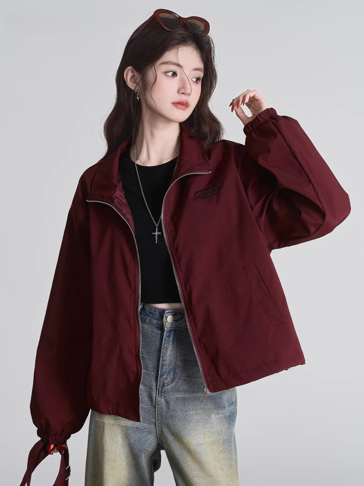 Woman wearing a burgundy bomber jacket with a full zip closure and stand-up collar.